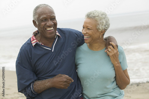 Cheerful African American mature couple with arms around at the beach