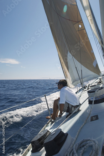 Side view of a man sitting on sailboat deck at the ocean