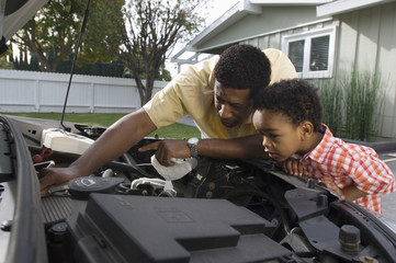 Man checking the engine of car with little boy looking at it