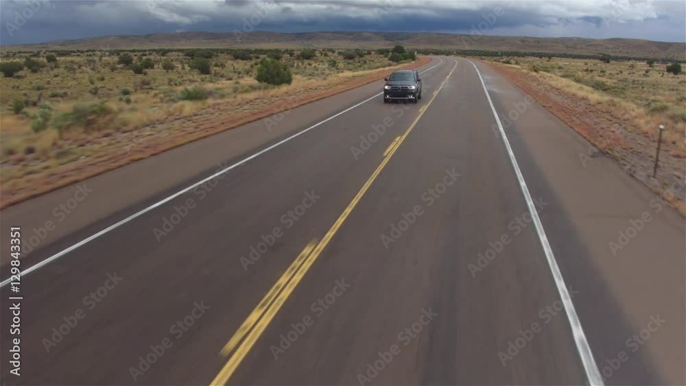 AERIAL: Black car driving on wet empty countryside road in bad rainy weather AERIAL: Black car driving on wet empty countryside road in bad rainy weather