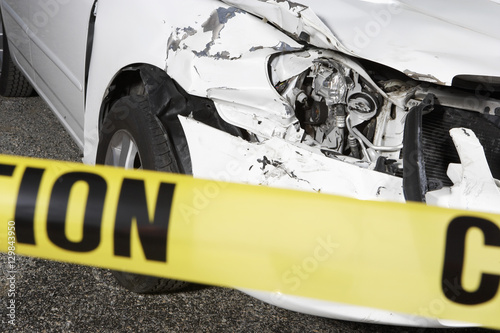 Closeup of a cropped damaged car behind warning tape at an accident scene