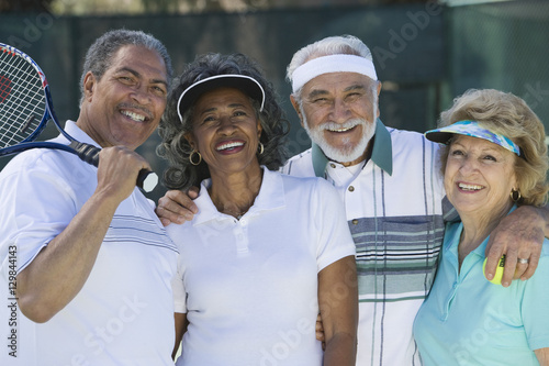 Portrait of happy senior friends in sportswear at tennis court