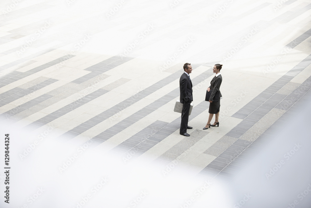 High angle view of businessman and businesswoman standing in outdoor plaza