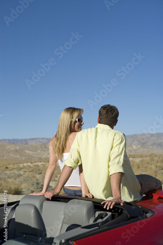 Rear view of young couple sitting at backside of car looking at view