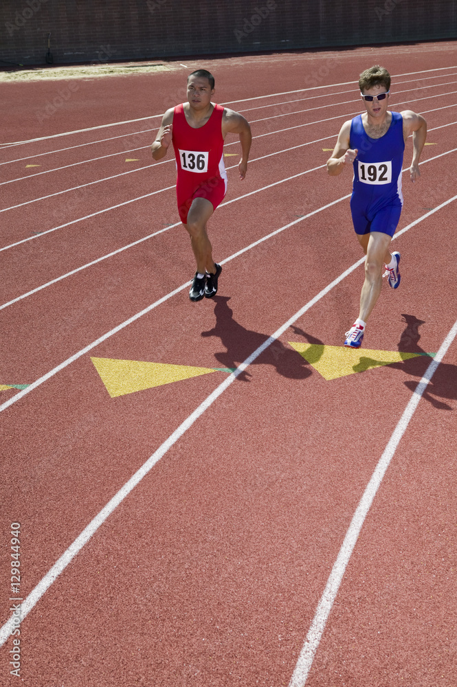 Two male athletes running on race track