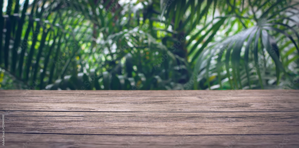 Empty plank brown wood table top with blur green tree background. Empty plank brown wood table top with blur green tree background.