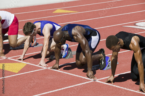 Multiethnic male athletes at starting line on racetrack