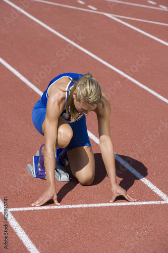 Full length of Caucasian female athlete ready to race on track and field