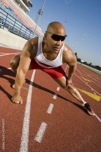 Full length of an African American male athlete warming up on race course