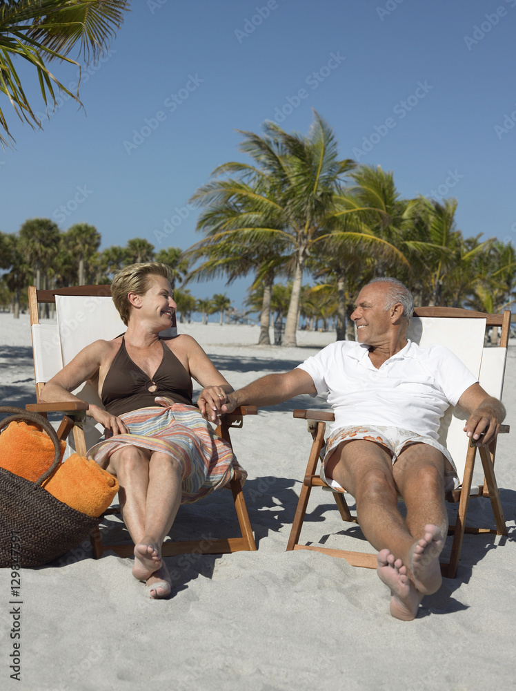 Happy senior couple on deckchairs during beach vacation