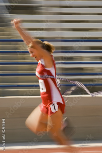 Photography Blurred motion of excited female athlete runner crossing the finishing line with