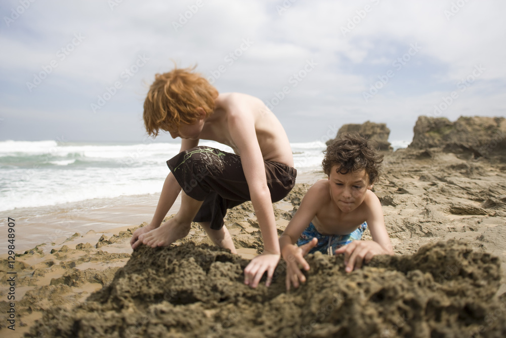 Young preadolescent boys playing in sand at beach Young preadolescent boys playing in sand at beach