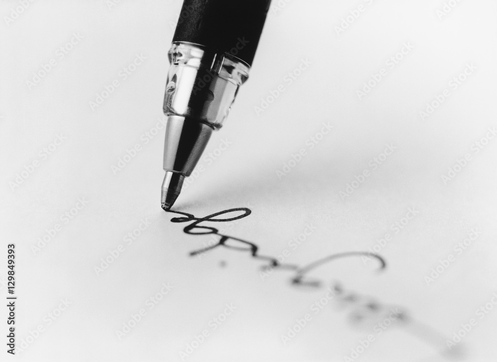 Fototapeta premium Tip of pen writing on paper (b&w) (close-up)