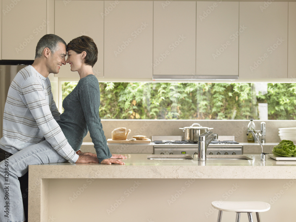 Happy couple rubbing noses at kitchen counter