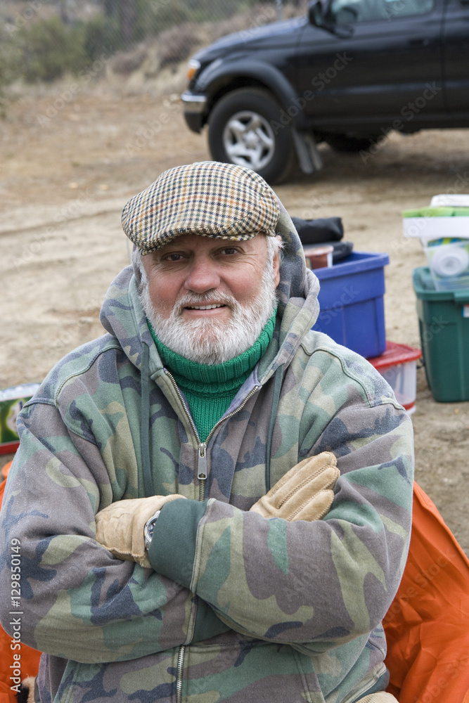 Portrait of confident senior man with hands folded on camping trip