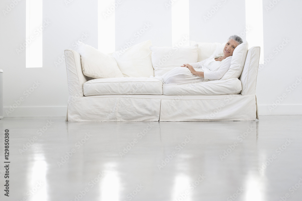 Full length portrait of senior woman sitting on sofa in spacious room Full length portrait of senior woman sitting on sofa in spacious room