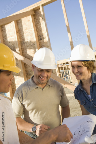 Three architects with blueprint discussing at construction site
