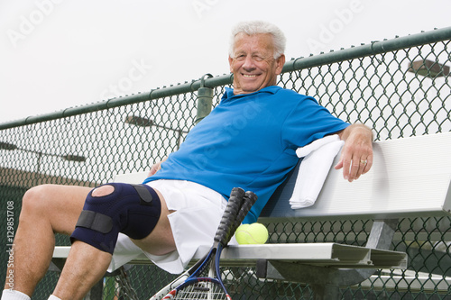 Schilderij op canvas Portrait of a happy senior man relaxing on bench after playing tennis