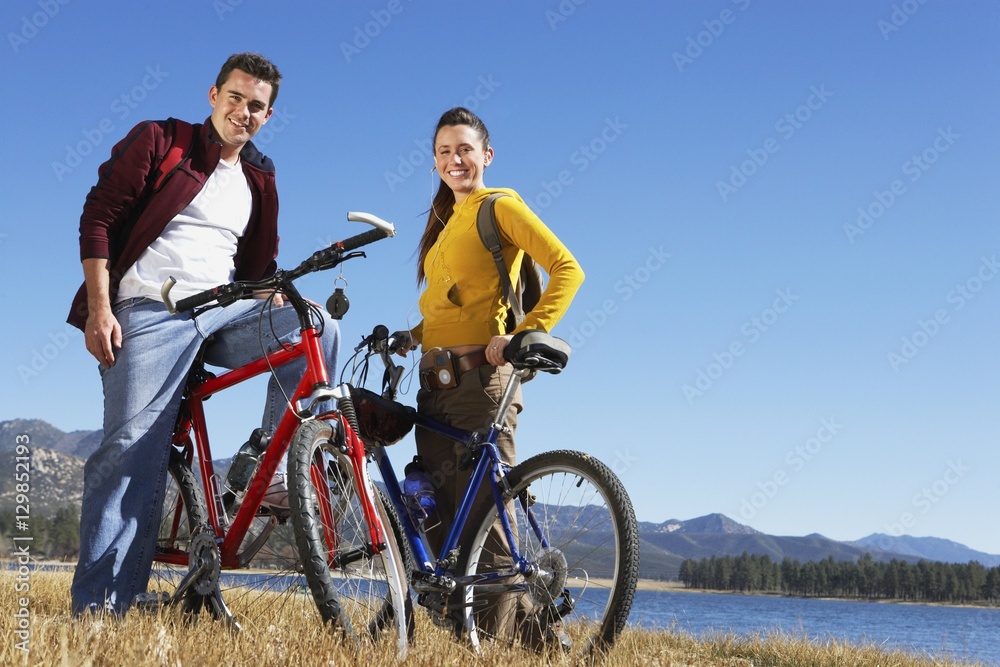 Full length portrait of Caucasian couple standing with their bicycles Full length portrait of Caucasian couple standing with their bicycles
