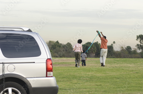 Rear view of African American family flying kite in the park