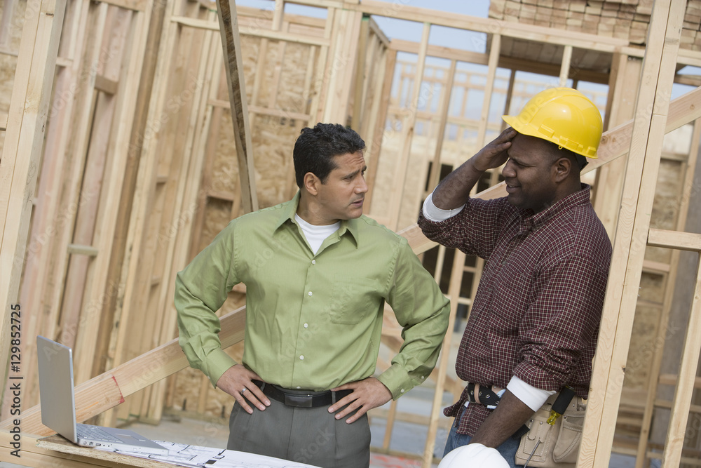 Engineer and foreman discussing plans while looking at each other Engineer and foreman discussing plans while looking at each other
