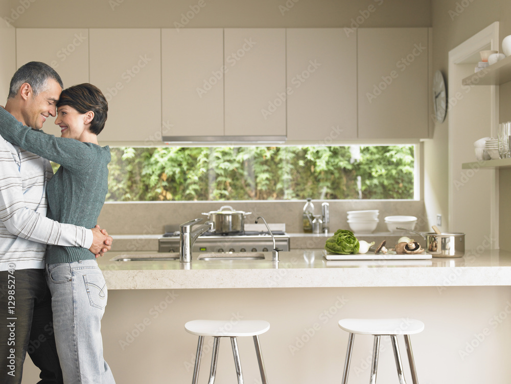 Profile shot of man and woman embracing in kitchen Profile shot of man and woman embracing in kitchen