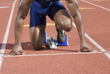 Low section of African American male athlete at starting block in race track