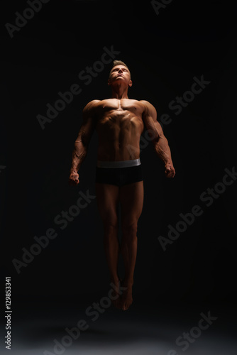 Muscular bodybuilder posing on black background. © Wisky