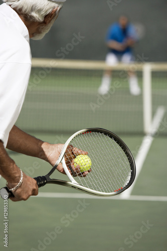 Senior tennis player with racket ready to serve a tennis ball