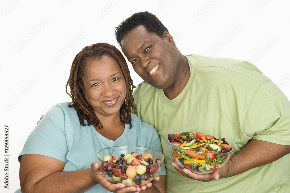 Portrait of happy obese couple holding bowl of salad isolated over white background