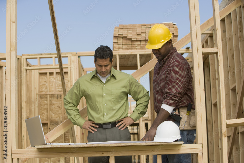 Engineer and foreman discussing plans while looking at the blueprint