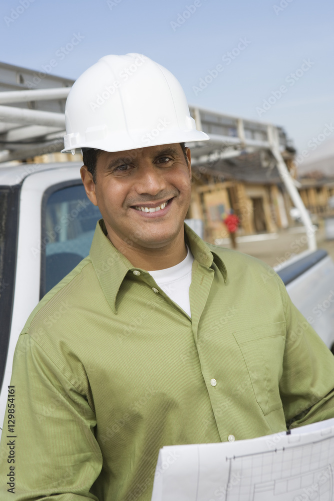 Portrait of a smiling construction worker with blueprints Portrait of a smiling construction worker with blueprints