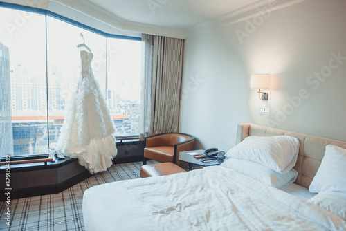 luxury bridal gown in hotel room. Wedding dress hanging in bridal suite. Beautiful wedding dress hanging in the bride's room photo