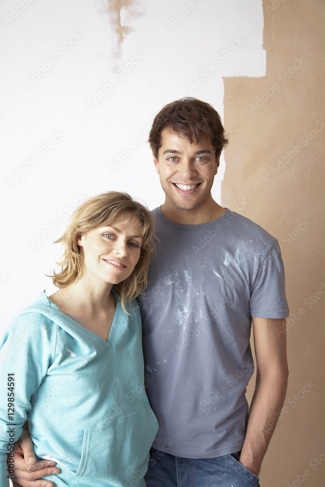 Portrait of happy couple embracing in front of partially painted wall