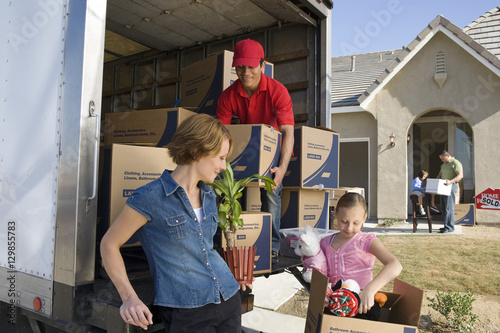 Canvas-taulu Family and worker unloading truck of cardboard boxes
