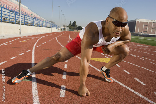 Full length of an African American male athlete warming up before race