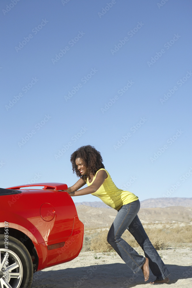 An African American young female pushing the car on sunny day