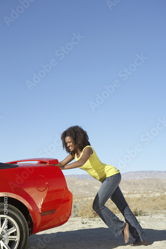 An African American young female pushing the car on sunny day