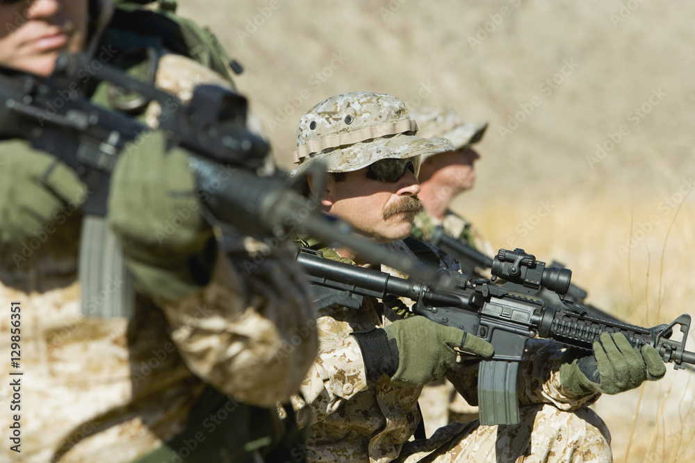Three soldiers with rifles patrolling during war Three soldiers with rifles patrolling during war