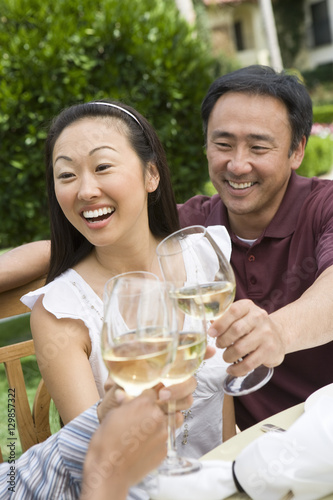 Happy mature Asian couple with friends toasting wine