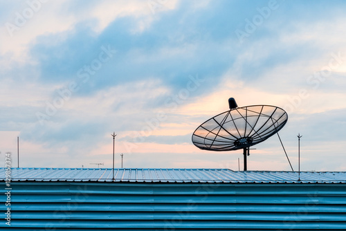 Satellite dish transmission data on background sunrise