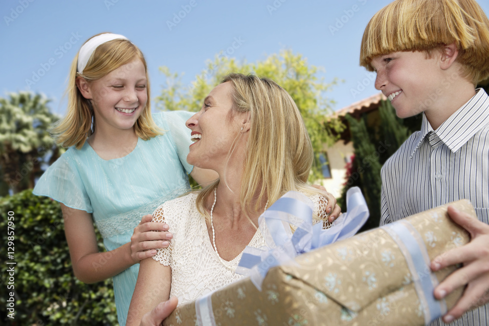 Happy mother receiving gift from children outdoors