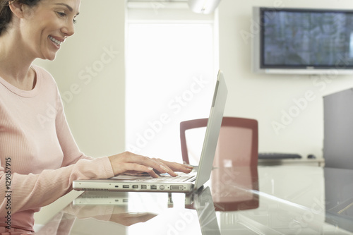 Side view of smiling young businesswoman using laptop in office