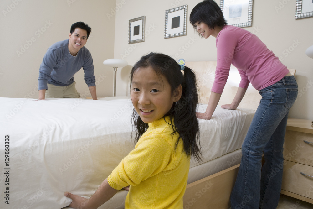 Father and daughter helping mother in preparing bed at home Father and daughter helping mother in preparing bed at home