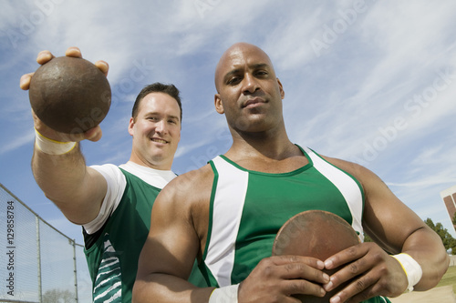 Portrait of male athletes with shot put and discus on track and field