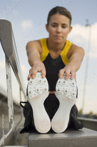 Female Caucasian athlete exercising on stadium bench