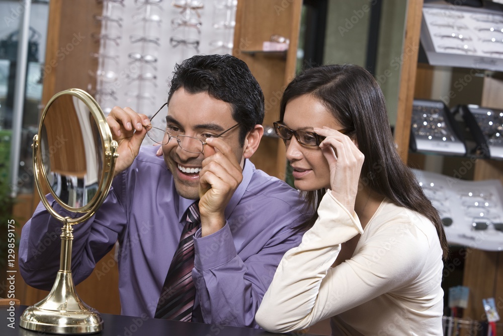 Happy Hispanic couple trying on glasses at shop