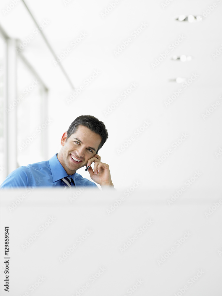 Portrait of smiling young businessman using cell phone at office Portrait of smiling young businessman using cell phone at office