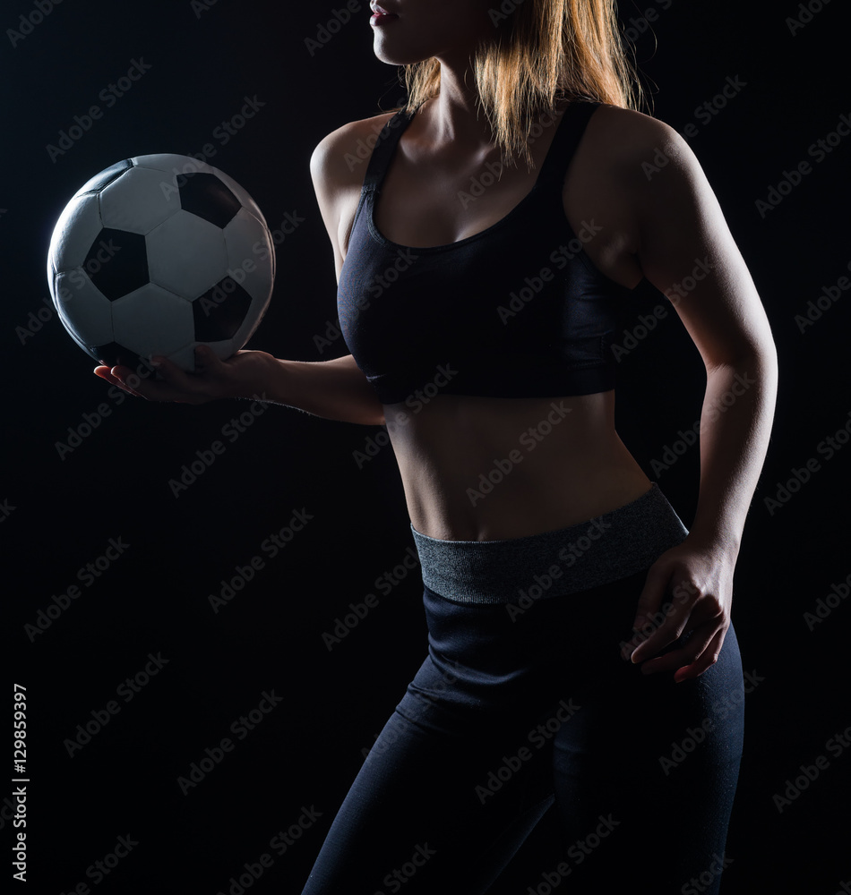 Beautiful woman holding a football black background Beautiful woman holding a football black background