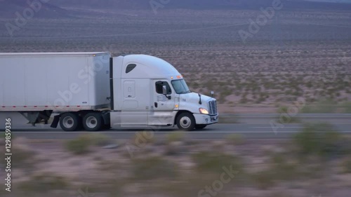 CLOSE UP: Freight semi truck driving and transporting goods on empty highway